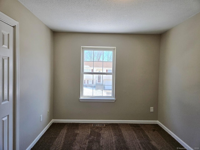 unfurnished room featuring a textured ceiling, dark colored carpet, visible vents, and baseboards