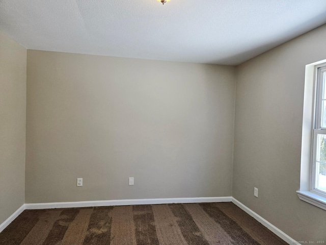 empty room with dark colored carpet and baseboards