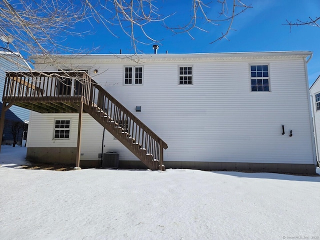 snow covered house featuring central air condition unit, stairs, and a wooden deck