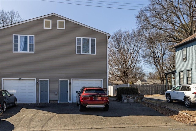 view of side of property featuring driveway, a garage, and fence