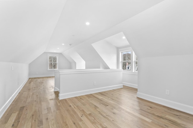 bonus room with baseboards, lofted ceiling, a wealth of natural light, and light wood-style floors