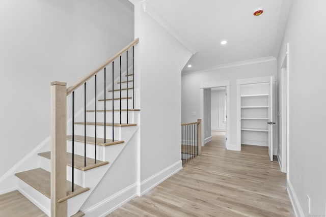 stairs with baseboards, ornamental molding, wood finished floors, and recessed lighting