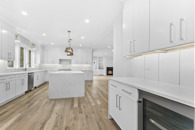 kitchen featuring a kitchen island, wine cooler, a lit fireplace, white cabinetry, and stainless steel dishwasher