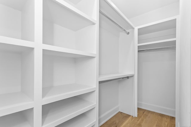 walk in closet with light wood finished floors