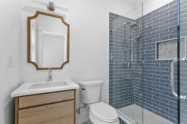 bathroom with tiled shower, vanity, and toilet