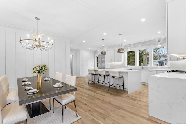 dining area featuring light wood-type flooring, a decorative wall, and crown molding