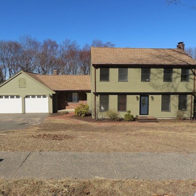 colonial house featuring a garage, driveway, and a chimney