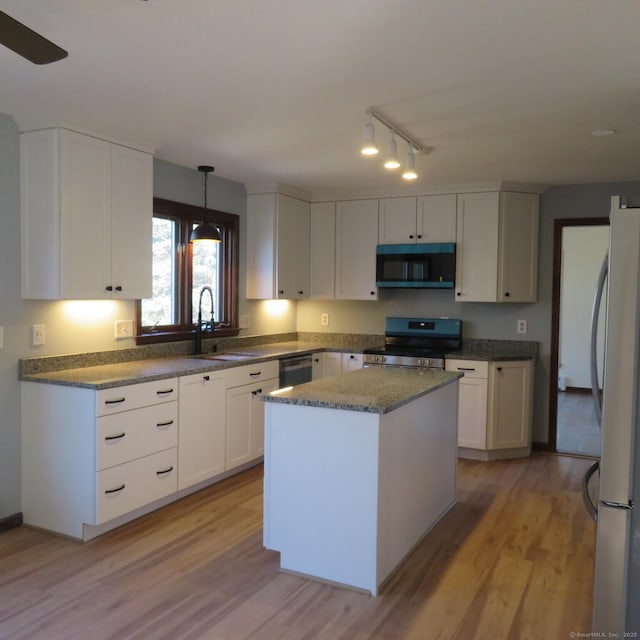 kitchen featuring light wood finished floors, a sink, stainless steel appliances, white cabinets, and a center island