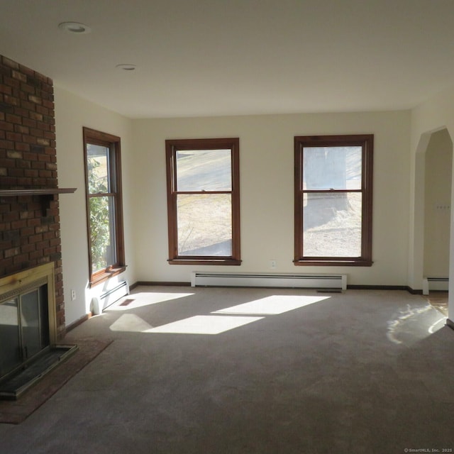 unfurnished living room with a brick fireplace, arched walkways, carpet floors, and a baseboard radiator