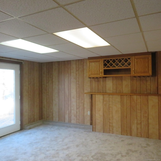 below grade area featuring wooden walls, carpet flooring, and a paneled ceiling