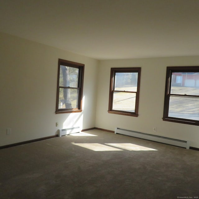 carpeted spare room with a baseboard heating unit and baseboards