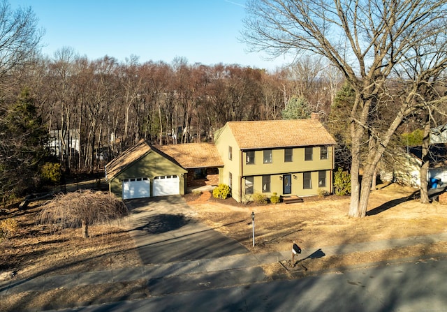 view of front of home with a garage, driveway, and a chimney