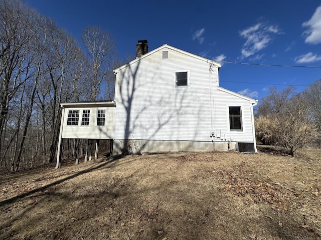 view of property exterior featuring a chimney and central AC