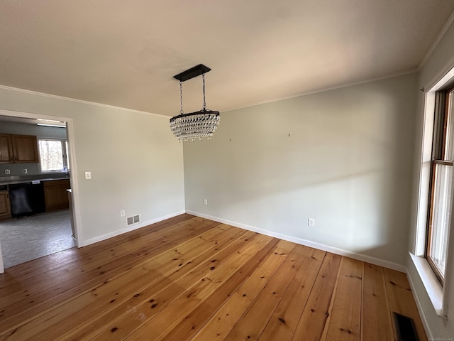 unfurnished dining area featuring hardwood / wood-style flooring, baseboards, visible vents, and crown molding