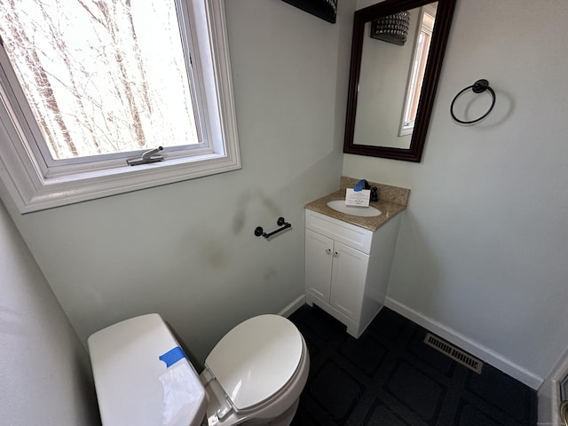 half bathroom featuring toilet, baseboards, visible vents, and vanity