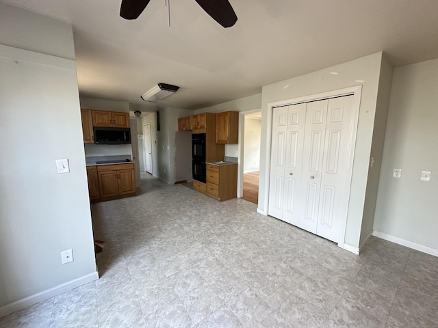 interior space with baseboards, black appliances, ceiling fan, and brown cabinets