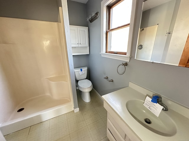 bathroom featuring baseboards, a shower stall, toilet, and vanity