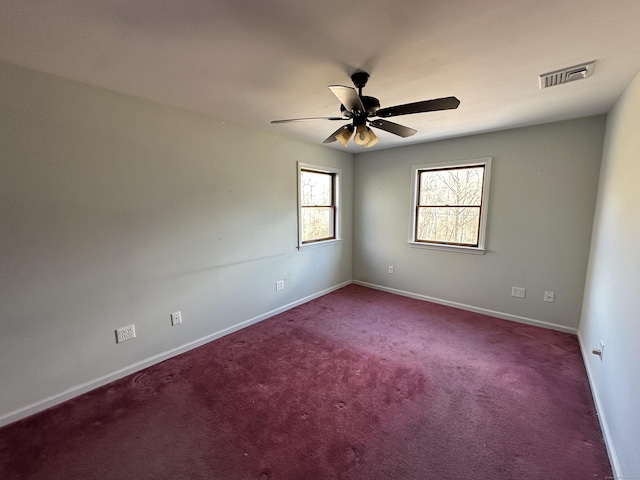 empty room with carpet flooring, visible vents, ceiling fan, and baseboards