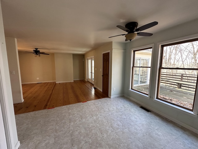 spare room with ceiling fan, visible vents, and baseboards