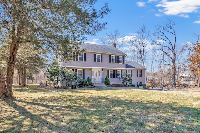 colonial-style house with a chimney and a front lawn