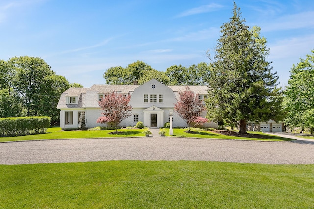 colonial inspired home featuring a gambrel roof and a front lawn