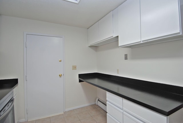 kitchen featuring built in desk, light tile patterned floors, dark countertops, baseboard heating, and white cabinetry