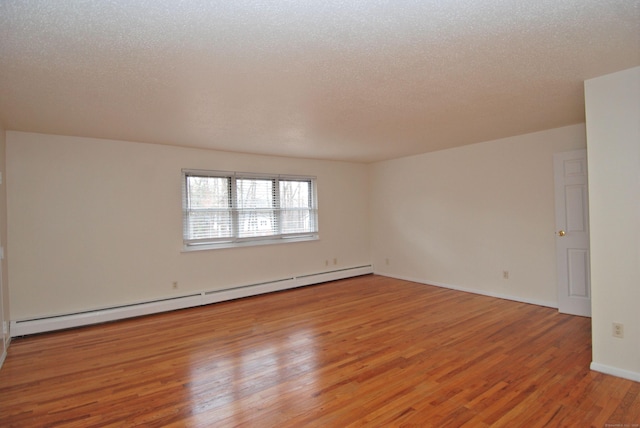 spare room with baseboards, light wood-style flooring, baseboard heating, and a textured ceiling