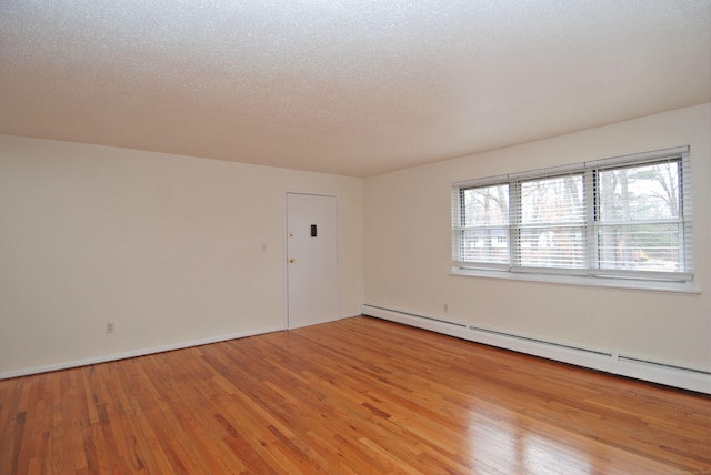 unfurnished room featuring a textured ceiling, a baseboard radiator, and light wood-style flooring