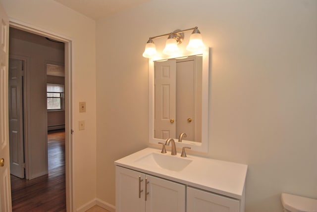 bathroom featuring baseboards, toilet, wood finished floors, baseboard heating, and vanity