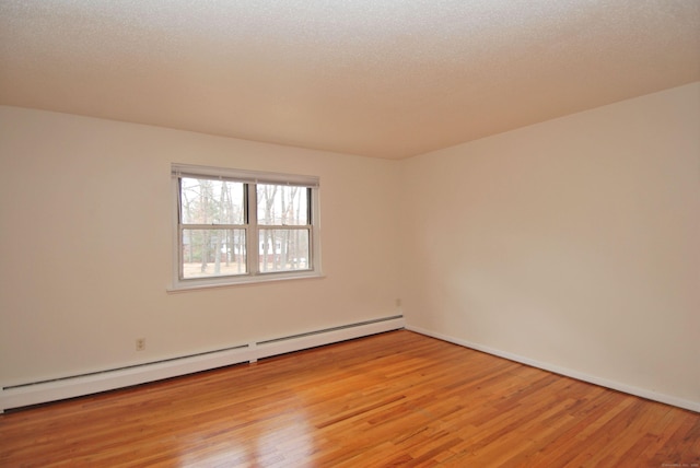 spare room with light wood-type flooring, baseboards, a textured ceiling, and baseboard heating