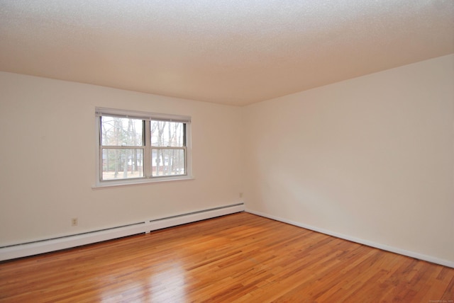 unfurnished room with a baseboard heating unit, light wood-type flooring, a textured ceiling, and baseboards