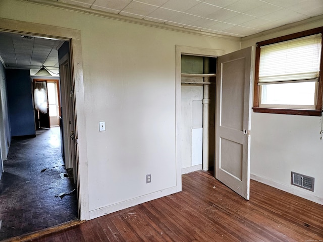 unfurnished bedroom with a closet, visible vents, dark wood-type flooring, and baseboards