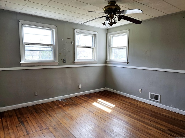 unfurnished room with visible vents, a ceiling fan, baseboards, and hardwood / wood-style floors