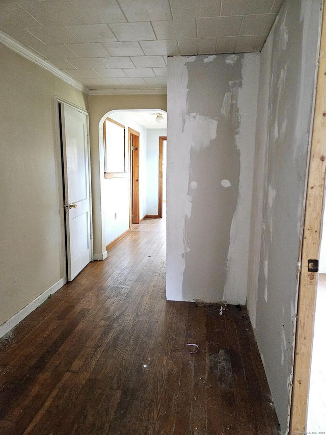 unfurnished room featuring hardwood / wood-style flooring, crown molding, baseboards, and arched walkways