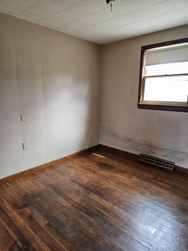 spare room with baseboards, visible vents, and wood-type flooring