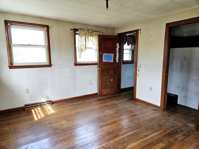 unfurnished room featuring hardwood / wood-style flooring, baseboards, and visible vents