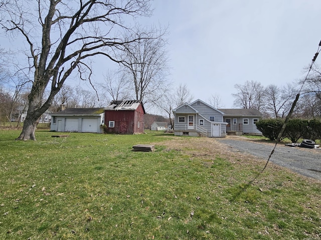 view of yard with a garage, an outbuilding, and driveway