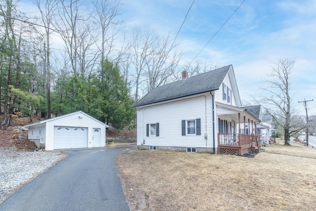 view of side of home with an outbuilding, covered porch, a shingled roof, a garage, and a chimney