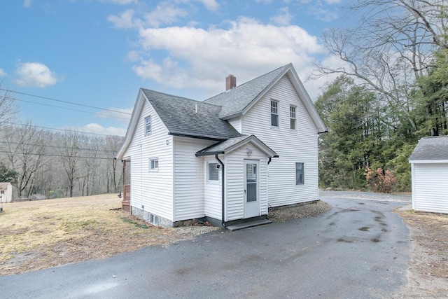 view of side of home with roof with shingles and a chimney