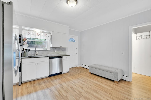 kitchen with a sink, baseboard heating, appliances with stainless steel finishes, and white cabinets