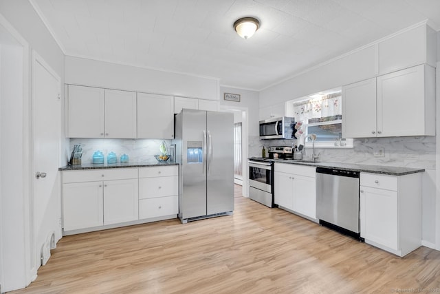 kitchen featuring appliances with stainless steel finishes, white cabinetry, light wood-style floors, and a sink