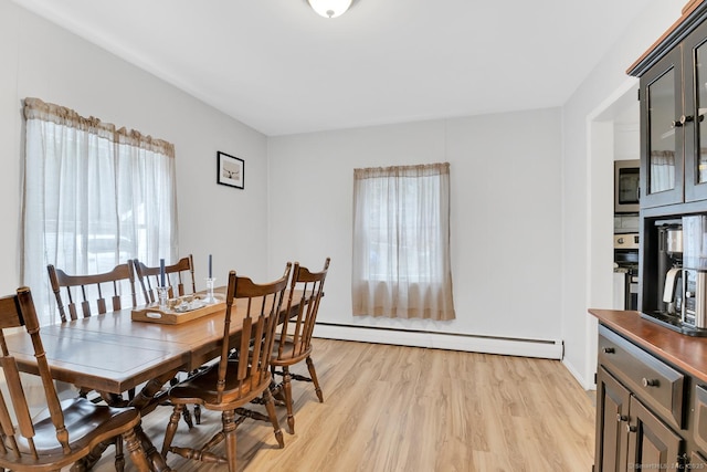 dining room featuring plenty of natural light, light wood-type flooring, and a baseboard heating unit