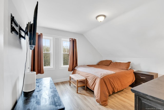 bedroom with lofted ceiling, baseboards, and light wood-type flooring