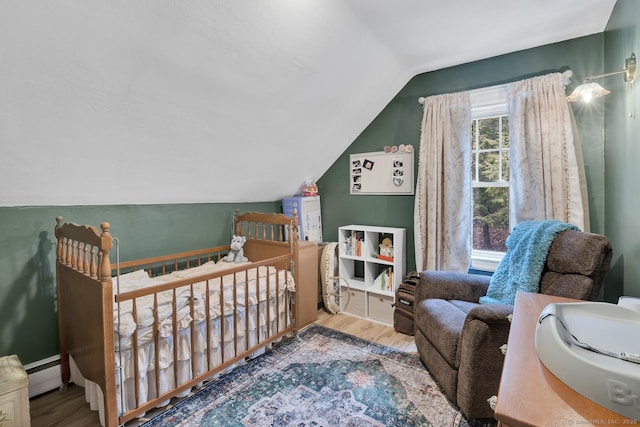 bedroom with a baseboard radiator, lofted ceiling, and wood finished floors