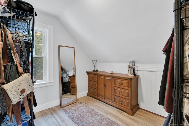 walk in closet with light wood-style floors and vaulted ceiling