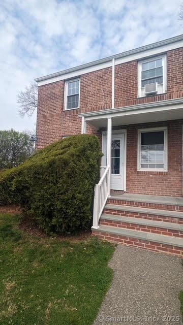 entrance to property with a porch and brick siding