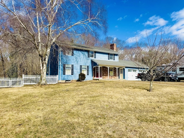 colonial inspired home with a front yard, fence, a porch, an attached garage, and a chimney