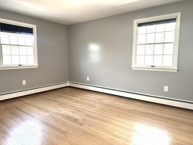 spare room featuring a baseboard heating unit and hardwood / wood-style flooring