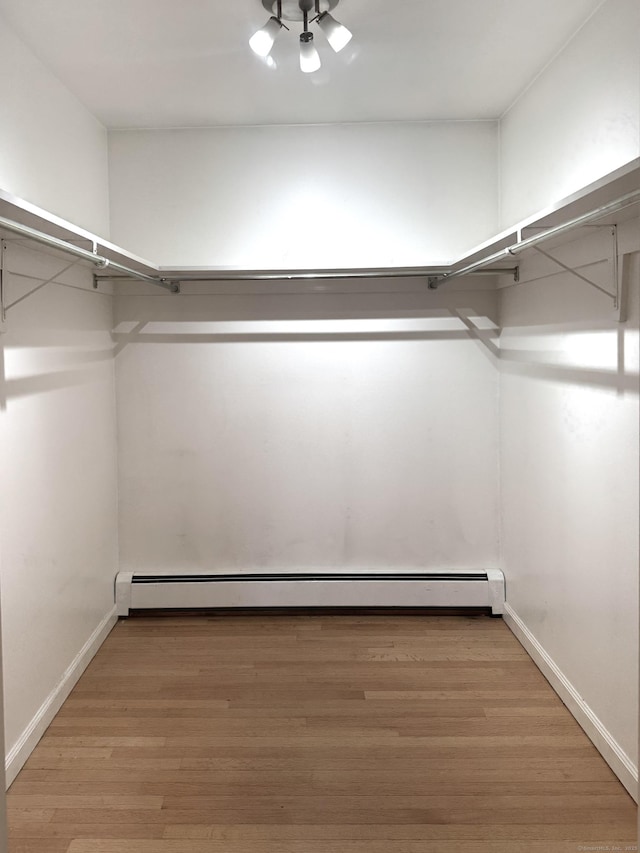 spacious closet with light wood-type flooring and a baseboard heating unit