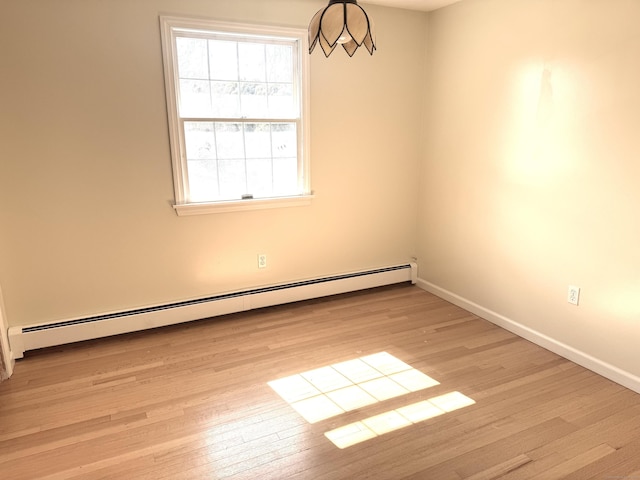 empty room with baseboards, light wood-type flooring, and baseboard heating